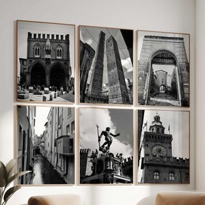 Könnte beinhalten: Sechs gerahmte Schwarz-Weiß-Fotografien italienischer Architektur hängen an einer weißen Wand. Die Bilder zeigen Gebäude, Straßen und Denkmäler. Zwei beige Sessel mit Metallrahmen und ein kleiner Tisch stehen vor der Wand.