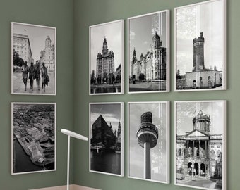 May include: A white desk with three drawers and small leather pulls, a white lamp, and a white chair. On the sage green wall are seven framed black and white photographs of city architecture, including a tower with the text Radio City 96.7.