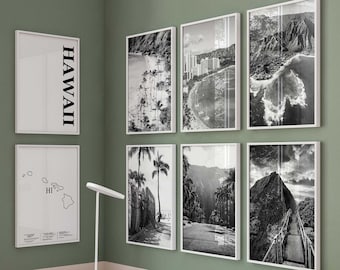May include: A white desk with three drawers, a white chair, and a white lamp. On the wall are eight framed black and white prints featuring Hawaii landscapes, a map with the text HAWAII and HI, and various coastal and mountain scenes in vertical frames.