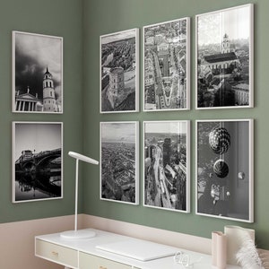 Puede incluir: Un escritorio blanco con tres cajones y una silla blanca delante. El escritorio está contra una pared verde con fotos enmarcadas en blanco y negro de paisajes urbanos y globos aerostáticos.