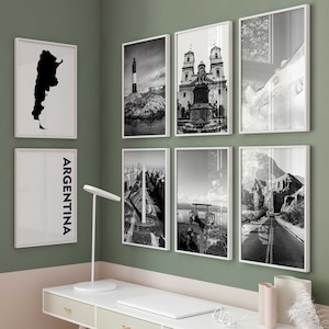 May include: A white desk with three drawers and gold handles. A white chair sits in front of the desk. The desk is decorated with a white laptop, a pair of glasses, and two vases with dried flowers. The wall behind the desk is painted in a light green colour and features a gallery wall of black and white photographs.