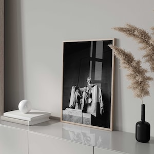 May include: Black and white photograph of a statue of Abraham Lincoln in a frame on a white shelf with two vases of dried pampas grass.