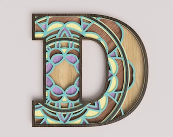Puede incluir: Una letra D de madera con un diseño de mandala decorativo en tonos azules, amarillos y morados. La letra está cortada en madera y tiene un marco marrón.