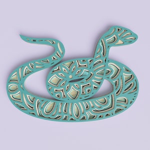 Peut inclure: Serpent en bois découpé au laser bleu turquoise avec un motif de mandala. Le serpent est enroulé en cercle.