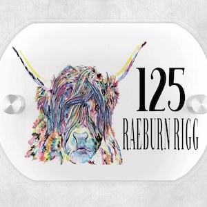 May include: A white oval sign with a colourful illustration of a Highland cow and the text "125 RAEBURN RIGG".