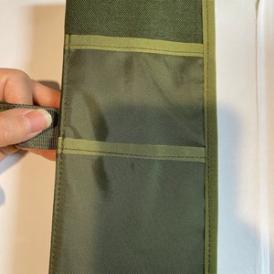 May include: A green canvas zippered pouch with multiple pockets and a carrying handle. The pouch is lined with a light green mesh fabric.