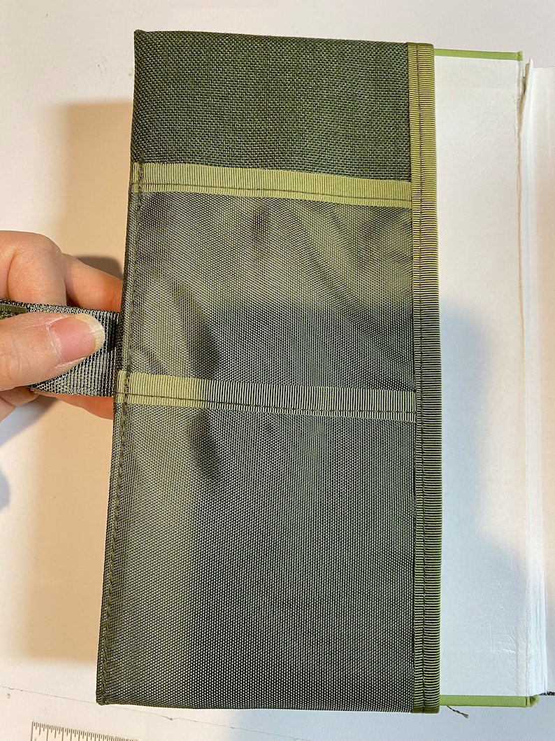 May include: A green canvas zippered pouch with multiple pockets and a carrying handle. The pouch is lined with a light green mesh fabric.