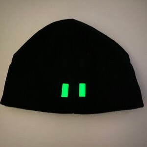 Puede incluir: Gorro negro con dos tiras reflectantes verdes en la parte delantera.