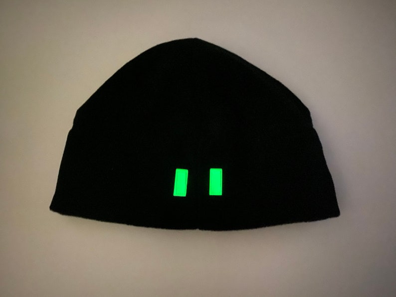 Puede incluir: Gorro negro con dos tiras reflectantes verdes en la parte delantera.