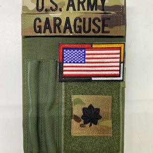 May include: A green tactical notebook with a velcro patch that says "U.S. ARMY GARAGUSE". The notebook also has a velcro patch with the American flag and a velcro patch with a black star.