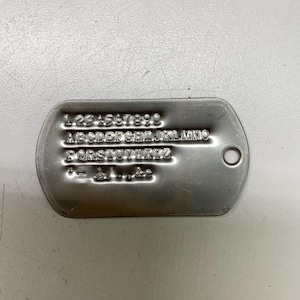 May include: A silver metal dog tag with the numbers 1234567890 and the letters of the alphabet A-Z engraved on it.