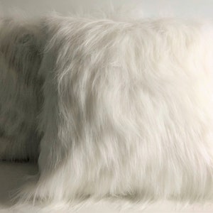 May include: Two white faux fur throw pillows. The pillows are soft and fluffy, and they would be perfect for adding a touch of luxury to any room.