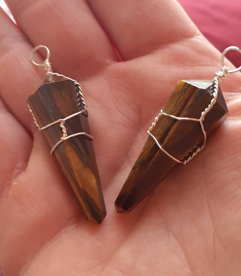 May include: Two gold-wrapped tiger's eye crystal pendants. The crystals are pointed and have a brown and gold color.