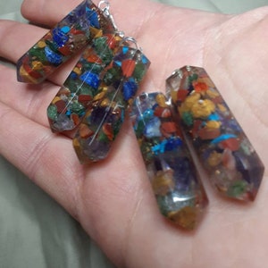 May include: Four colorful crystal pendants with silver loops. Each pendant is made of clear resin with embedded colorful stones, including red, orange, yellow, green, blue, and purple.