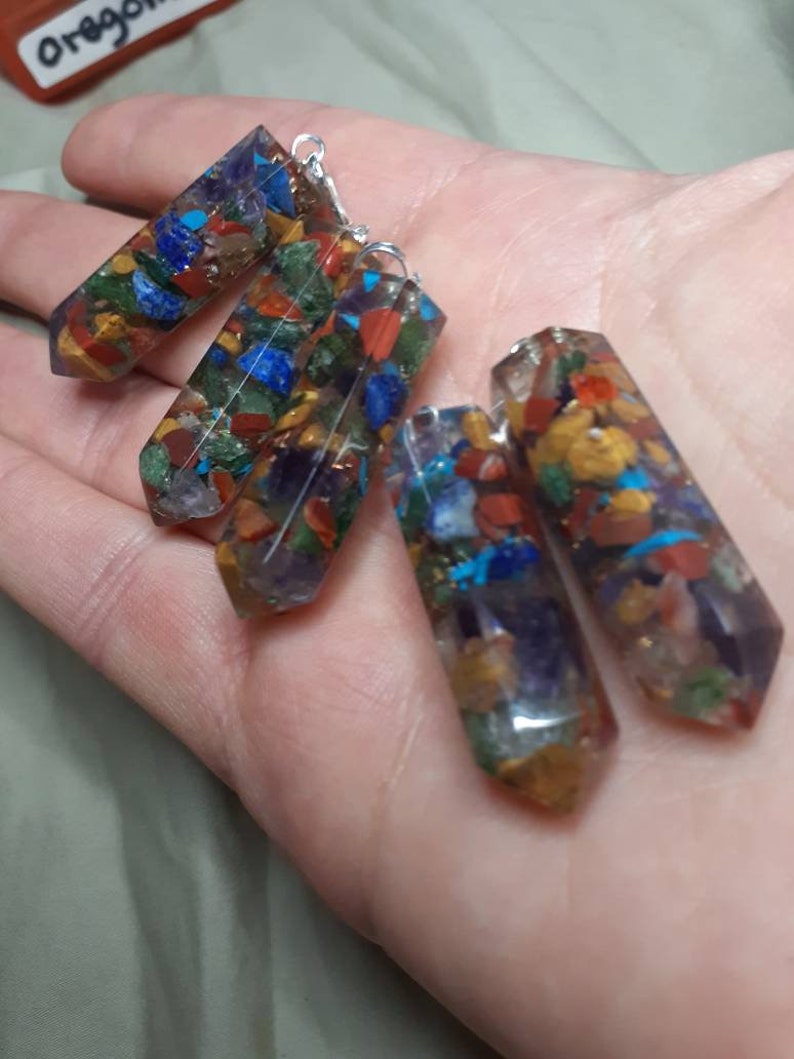 May include: Four colorful crystal pendants with silver loops. Each pendant is made of clear resin with embedded colorful stones, including red, orange, yellow, green, blue, and purple.