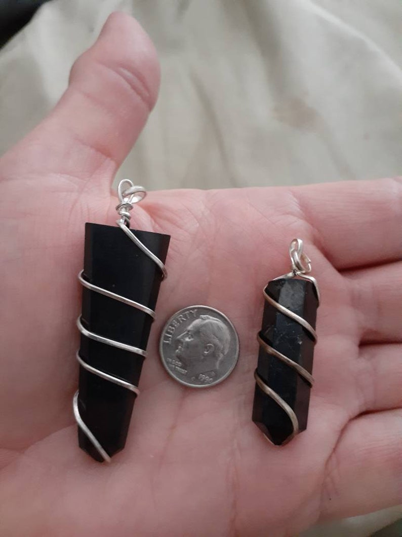 May include: Two black crystal pendants wrapped in silver wire. The larger pendant is about the size of a UK ten pence coin.