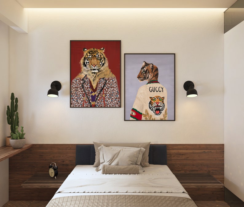 May include: Two framed illustrations of tigers. The first illustration features a tiger wearing a patterned jacket. The second illustration features a tiger wearing a white sweater with the word "GUCCI" and a tiger graphic.