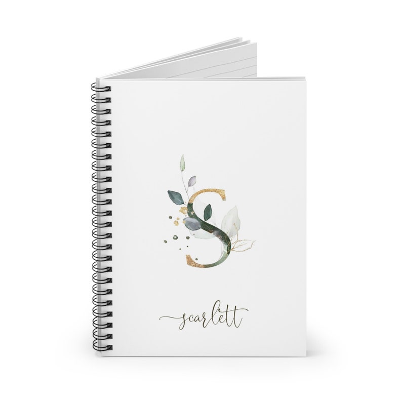 May include: A white spiral notebook with a gold and green watercolor letter S with leaves and gold dots. The name "scarlett" is written in cursive below the letter.