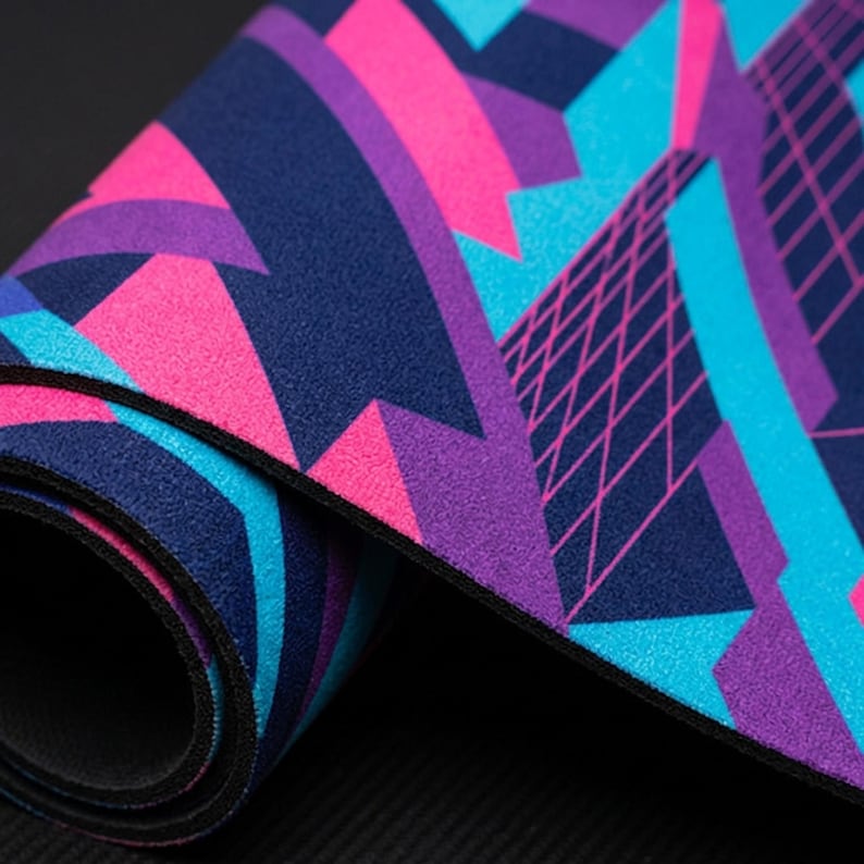 May include: A flexible rectangular mat featuring a vibrant geometric pattern in shades of bright pink, electric blue, deep purple, and navy blue. The surface displays sharp angular shapes and a fine grid-like texture across the colorful design.
