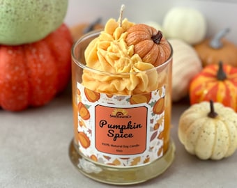 May include: A clear glass candle with a pumpkin spice scent, featuring a whipped orange wax top decorated with a small pumpkin figure. The label reads SunHavenCo Pumpkin Spice 100% Natural Soy Candle 10oz, surrounded by a pattern of autumn leaves and pumpkins.