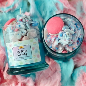 Puede incluir: Dos frascos de vidrio llenos de una vela de soja con aroma a algod&oacute;n de az&uacute;car azul y rosa. Los frascos est&aacute;n rodeados de algod&oacute;n de az&uacute;car rosa y azul. La etiqueta del frasco dice "Cotton Candy 100% Natural Soy Candle 10oz"
