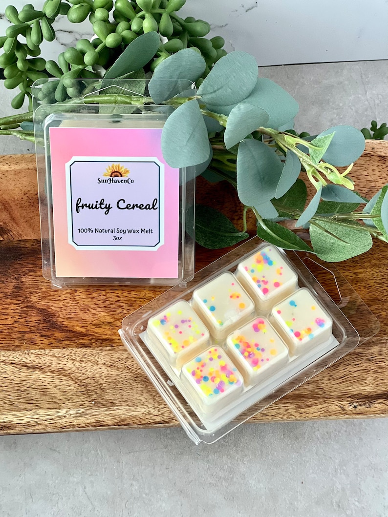 May include: Six white wax melts in a clear plastic container. The wax melts are topped with colourful sprinkles. The container has a label that reads "SunHavenCo fruity Cereal 100% Natural Soy Wax Melt 3oz."