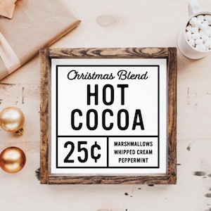 May include: A framed sign with a white background and black text that reads "Christmas Blend Hot Cocoa 25&cent; Marshmallows Whipped Cream Peppermint". The sign is in a rustic wooden frame.