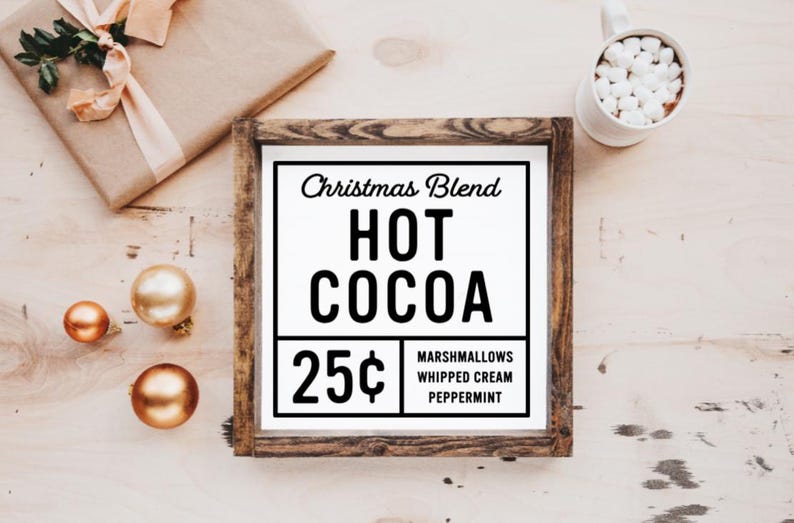 May include: A framed sign with a white background and black text that reads "Christmas Blend Hot Cocoa 25&cent; Marshmallows Whipped Cream Peppermint". The sign is in a rustic wooden frame.