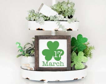 May include: A white tiered tray with green shamrock decorations and a sign that says "17 March" with a green shamrock graphic.