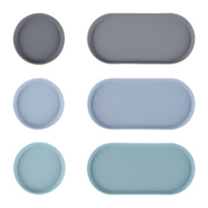 May include: Set of six round and oval trays in three colors: gray, light blue, and teal. The trays are made of a smooth, durable material and are perfect for serving snacks, drinks, or organizing small items.