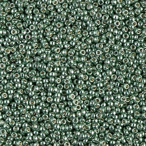 Puede incluir: Una imagen de primer plano de una gran cantidad de pequeñas cuentas de vidrio redondas de color verde. Las cuentas tienen un brillo metálico y son perfectas para la elaboración de joyas.