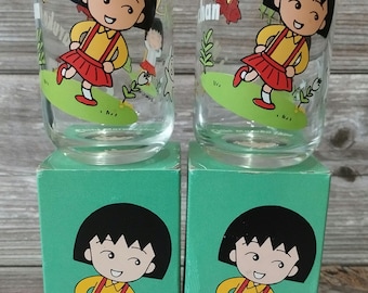 May include: Two clear glass cups with green and yellow cartoon characters on them. The cups are in their original boxes, which are green with a cartoon character on the front. The boxes say "Sakura" and "Chan" on them.