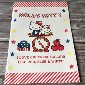 May include: A Hello Kitty themed print featuring Hello Kitty and a bunny on a scale, with red apples, a treasure chest, and stars. The text reads "I LOVE CHEERFUL COLORS LIKE RED, BLUE & WHITE!"