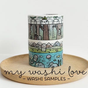 Puede incluir: Un conjunto de cuatro cintas washi con ilustraciones lindas de criaturas del bosque, montañas y escenas submarinas. Las cintas están en una bandeja de madera con el texto "my washi love - WASHI SAMPLES -" impreso en la parte inferior.