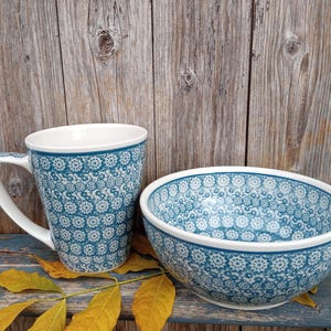 Könnte beinhalten: Eine blaue und weiße Keramiktasse und Schüssel mit einem Blumenmuster. Die Tasse hat einen Henkel und die Schüssel ist rund.