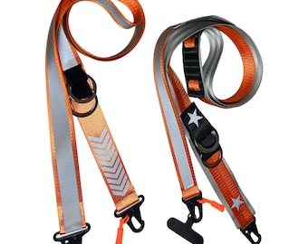 May include: Two orange and silver reflective straps with black buckles and white accents. One strap has a chevron pattern and the other has a star.