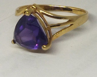 May include: A gold ring with a large, purple, triangular gemstone.