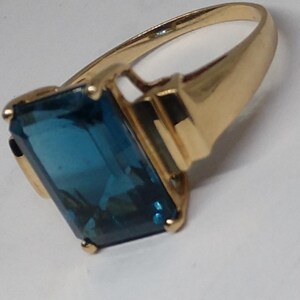 May include: A gold ring with a large, rectangular, blue gemstone.