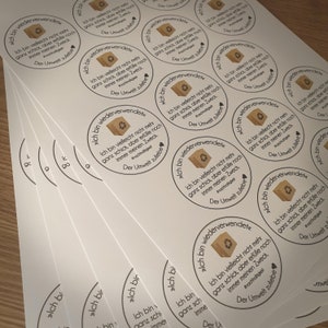 Puede incluir: Varias pegatinas redondas marrones y blancas con el texto "Ich bin wiederverwendet", que se traduce como "Soy reutilizado" en ingl&eacute;s. Las pegatinas presentan una peque&ntilde;a caja marr&oacute;n con un coraz&oacute;n y el texto "Der Umwelt zuliebe", que se traduce como "Por el bien del medio ambiente" en ingl&eacute;s.