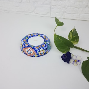Puede incluir: Un portavelas de cerámica azul y blanco con un diseño floral. El portavelas tiene un centro blanco para una vela.