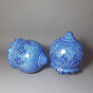 May include: Two blue and white ceramic hanging lamps with intricate floral designs and cut-out patterns. The lamps are decorated with gold accents.