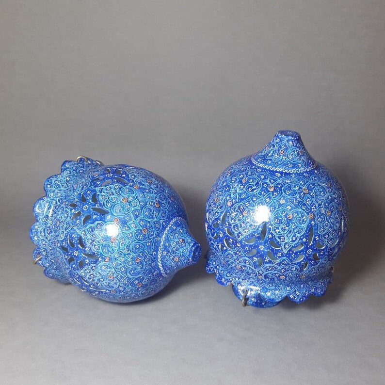 May include: Two blue and white ceramic hanging lamps with intricate floral designs and cut-out patterns. The lamps are decorated with gold accents.