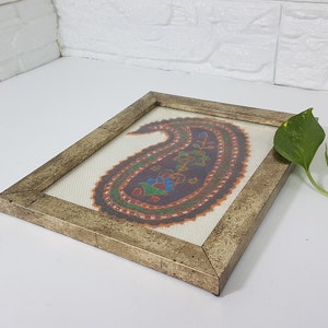 May include: A framed artwork featuring a colorful paisley design in shades of orange, green, blue, and purple. The frame is a distressed gold color.