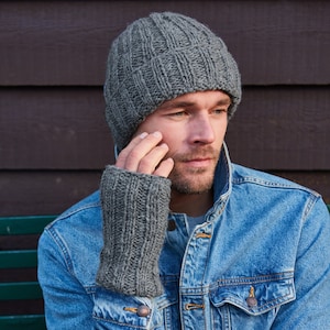 Peut inclure: Un homme portant un bonnet en tricot gris et des mitaines assorties. Il porte une veste en jean bleu.