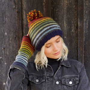 May include: A striped knitted hat with a pom pom on top and matching striped fingerless gloves. The hat and gloves are in shades of blue, green, yellow, orange, and red.