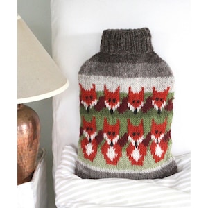 May include: A brown knitted hot water bottle cover with a pattern of red foxes on a green and brown background.