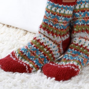 May include: A pair of colorful knitted socks with a red, white, blue, green, and orange pattern. The socks are made of wool and have a comfortable fit.