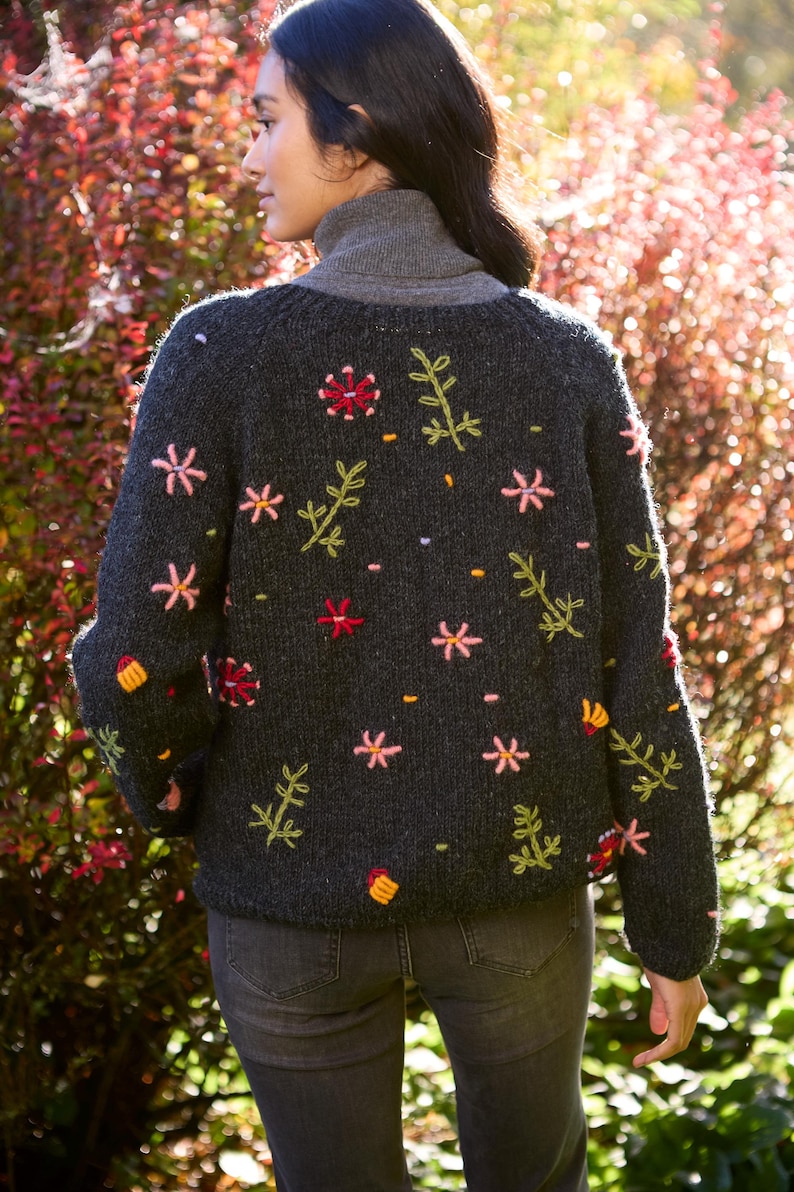 May include: A dark gray knitted cardigan with embroidered flowers and leaves in shades of pink, green, and yellow.