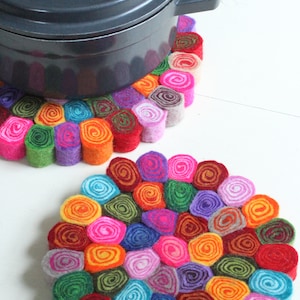 Peut inclure: Deux dessous de plat en feutre coloré, chacun composé d'un cercle de feutre roulé en différentes couleurs, dont le rose, le vert, le bleu, l'orange et le violet. Les dessous de plat sont parfaits pour protéger les surfaces des casseroles et poêles chaudes.