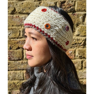 Puede incluir: Diadema de punto blanco con ribete rojo y botones de colores.